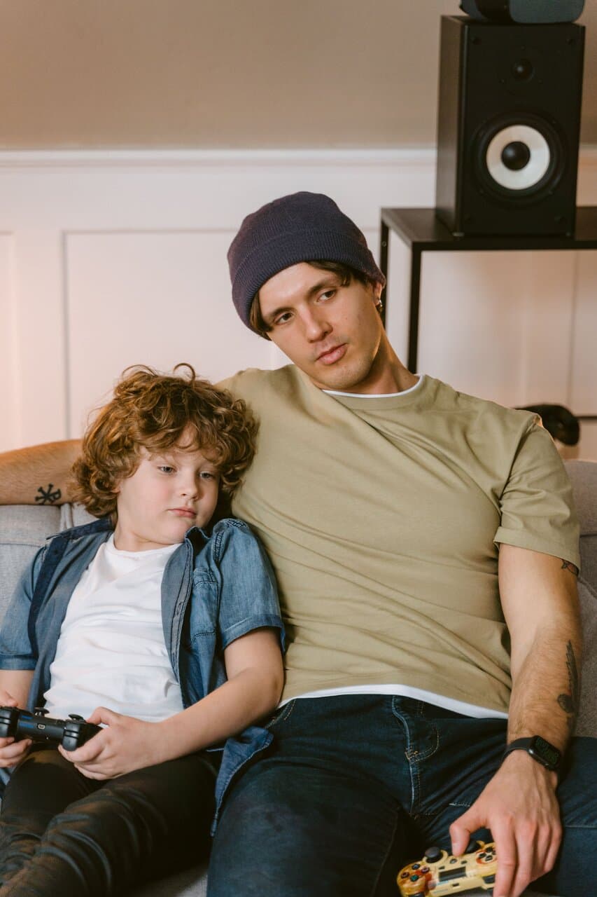 Father and son playing video games together on the sofa
