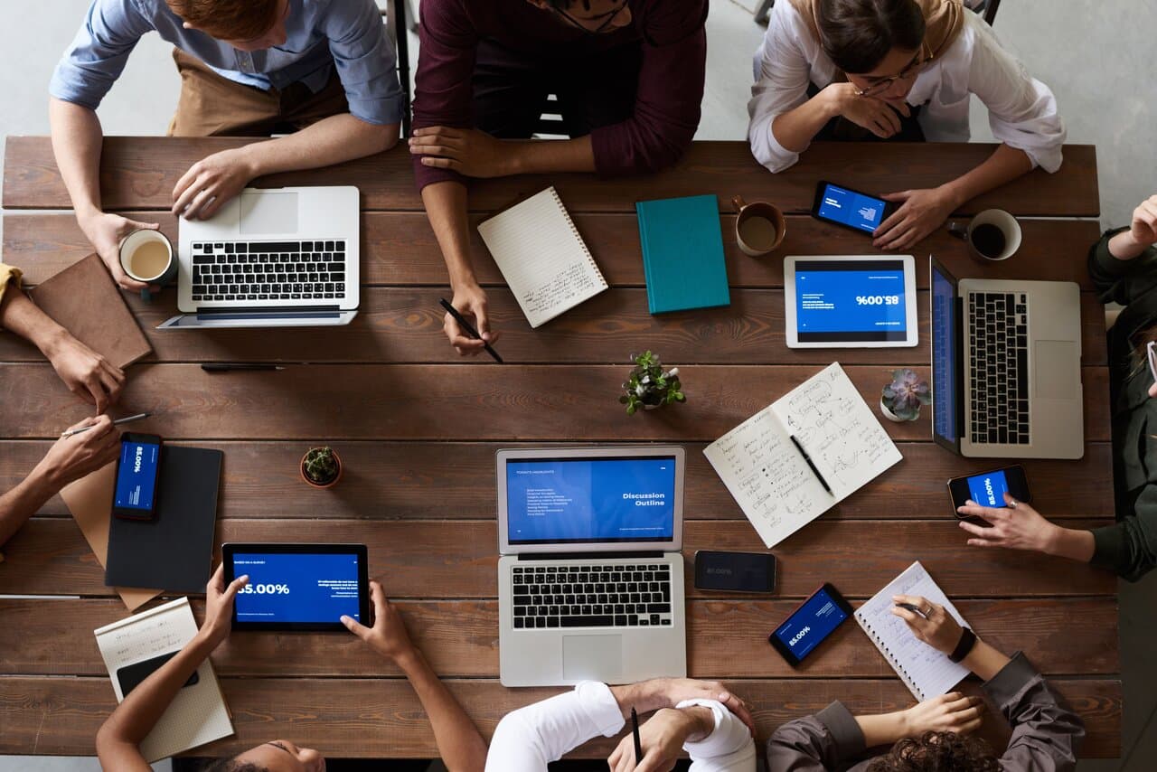 Product team collaborating around a table with laptops and tablets