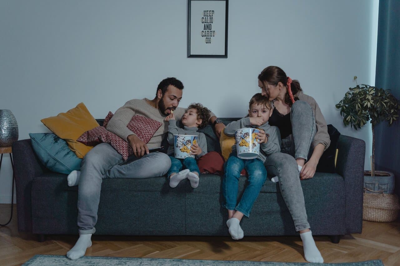 Family enjoying movie night with popcorn on the sofa